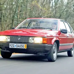 Czerwony Talbot jedzie przez las.
