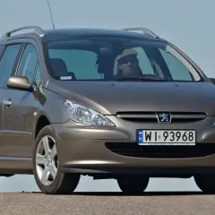 Brązowe kombi Peugeot 307 z kierowcą w jasnej czapce na tle błękitnego nieba.