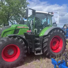 Zielony traktor Fendt 930 Vario z czerwonymi felgami, gotowy do pracy na polu.