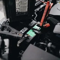 Podłączanie kabli rozruchowych do akumulatora w Daewoo Espero. Czerwony zacisk na biegunie dodatnim, czarny na ujemnym.