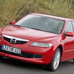Czerwona Mazda 6 2.0 benzyna w ruchu, za kierownicą uśmiechnięta kobieta.