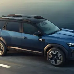 Niebieski Dacia Bigster 2025 na drodze, z nowoczesnym designem i relingami dachowymi.