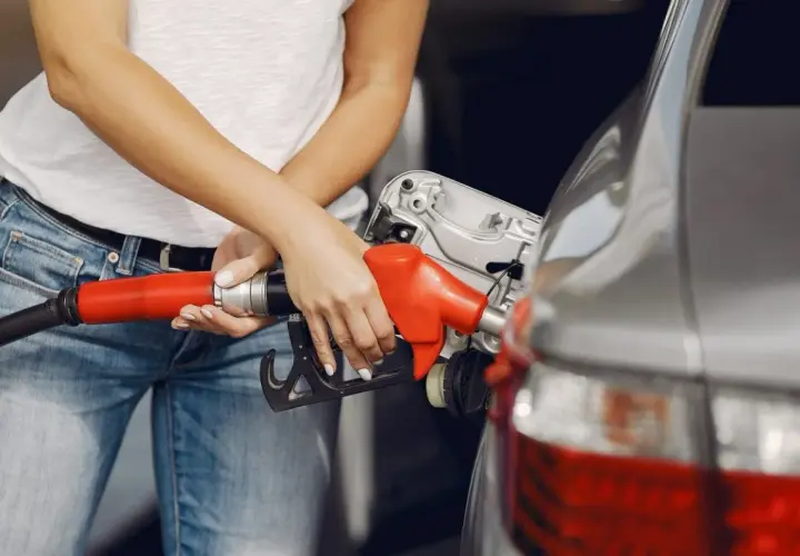 Kobieta tankuje samochód, trzymając czerwoną dyszę paliwową. N20.