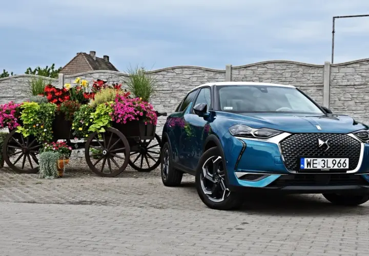 Niebieski DS 3 Crossback obok drewnianego wozu z kwiatami.
