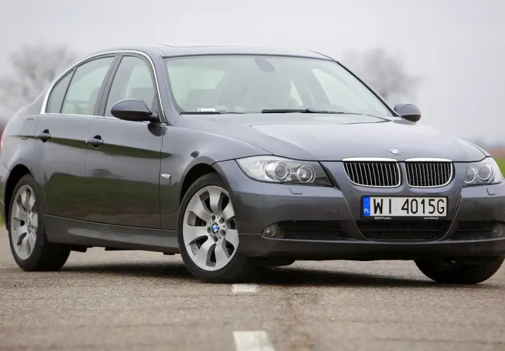 Szary sedan BMW E90 2.0 benzyna na drodze.