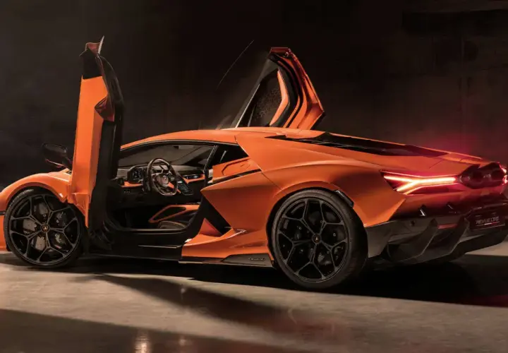 Pomarańczowy Lamborghini Revuelto z otwartymi drzwiami typu nożycowego, z widocznym wnętrzem i sportowymi felgami.