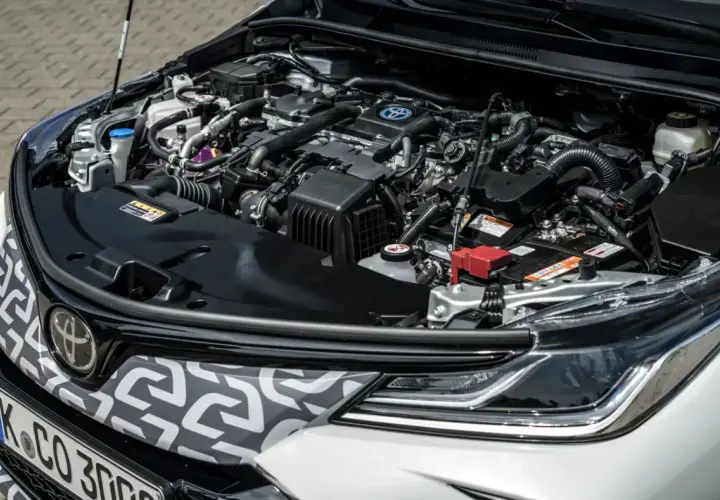 Silnik hybrydowy Toyoty Corolli 2022, z widocznym logo Toyoty i elementami układu napędowego.