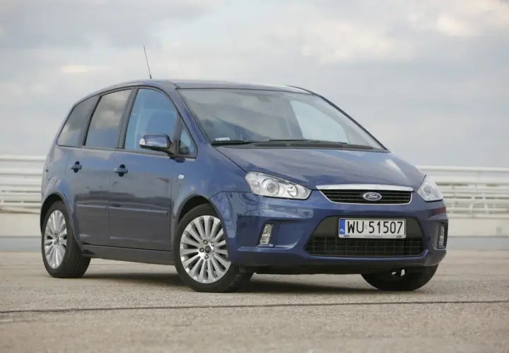 Niebieski Ford C-Max 1.6 benzyna z polskimi tablicami WU 51507 zaparkowany na betonowym placu.
