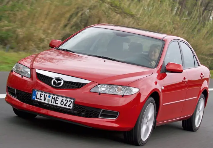 Czerwona Mazda 6 2.0 benzyna w ruchu, za kierownicą uśmiechnięta kobieta.