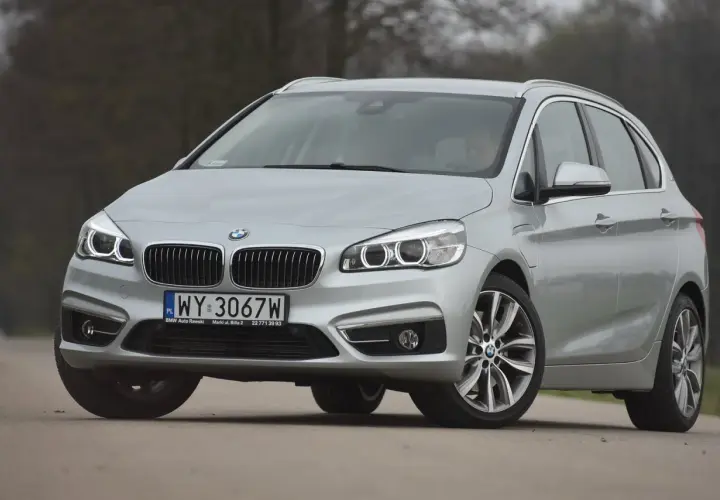 Srebrne bmw 218i na drodze, z przodu widoczna atrapa chłodnicy i reflektory.