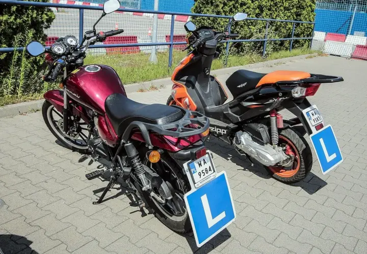 Dwa pojazdy z literą "L" na niebieskiej tablicy, sugerujące naukę jazdy.