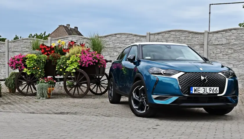 Niebieski DS 3 Crossback obok drewnianego wozu z kwiatami.