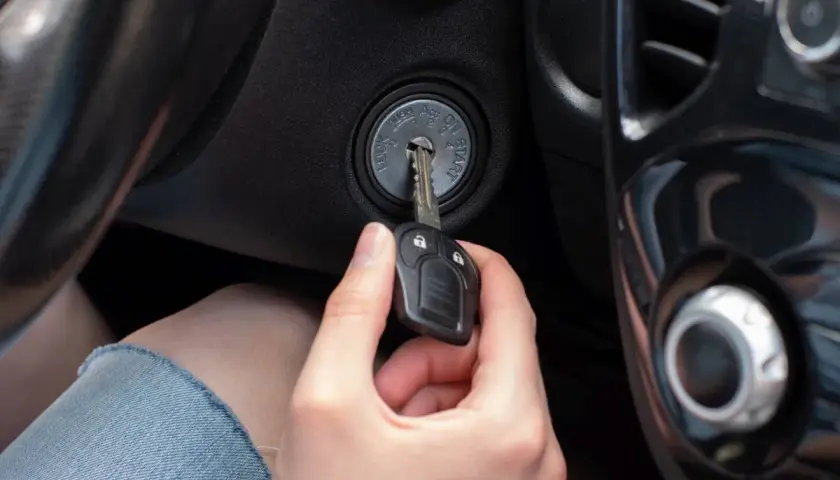 Dłoń wkłada kluczyk do stacyjki. To pokazuje, jak działa immobilizer, zabezpieczając auto przed kradzieżą.