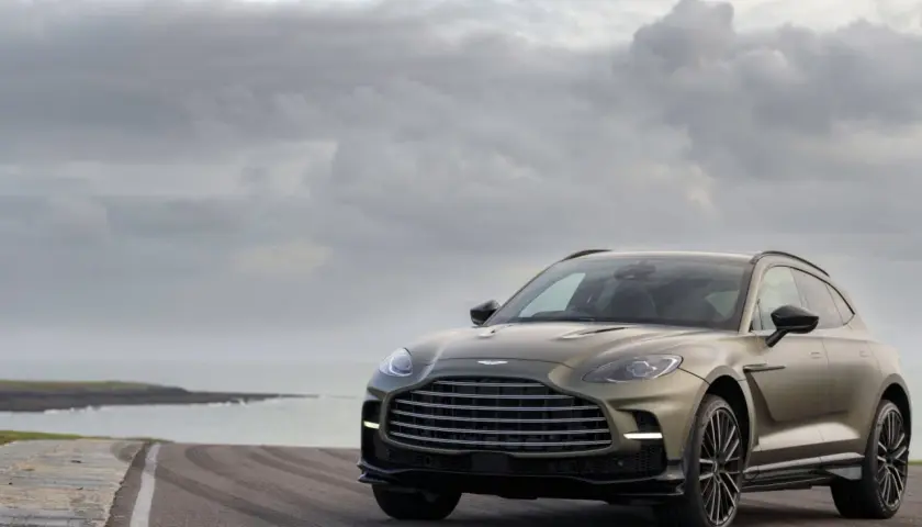 Aston Martin DBX 707 na tle pochmurnego nieba i morza. Luksusowy SUV prezentuje się majestatycznie na pustej drodze.