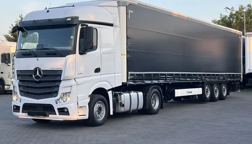 Biały Mercedes Actros MP4 z czarną plandeką naczepy Krone, gotowy do trasy.
