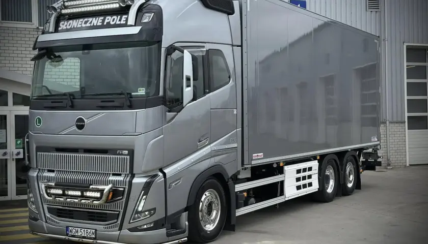 Srebrny Volvo FH16 z naczepą chłodniczą, ozdobiony dodatkowymi światłami i napisem "Słoneczne Pole".