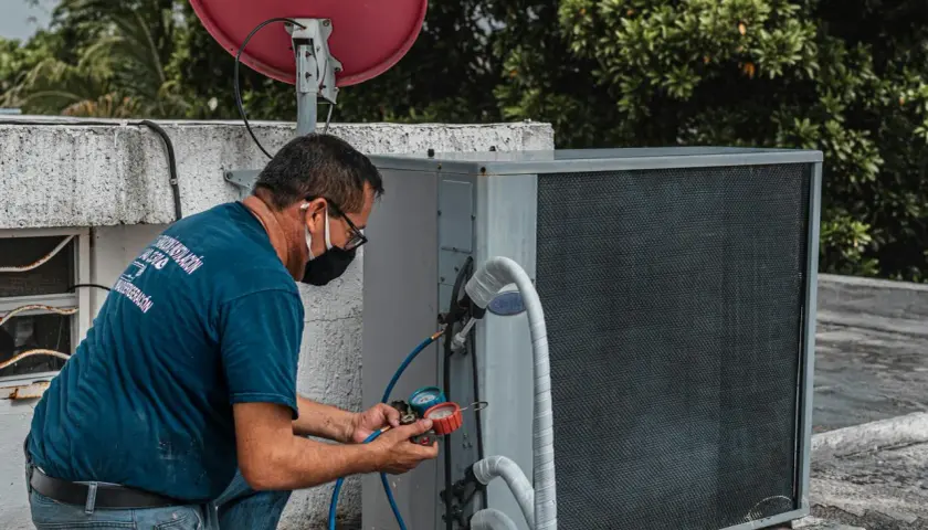 Technik sprawdza czujnik ciśnienia klimatyzacji za pomocą manometru.