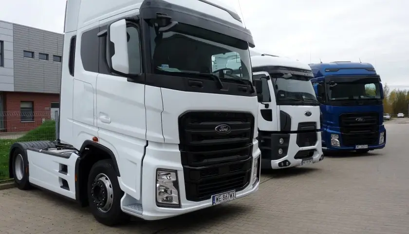Trzy ciężarówki Ford F650 stoją obok siebie. Biała, biała i niebieska ciężarówka.