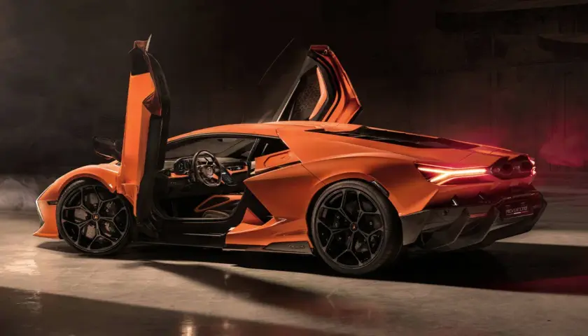 Pomarańczowy Lamborghini Revuelto z otwartymi drzwiami typu nożycowego, z widocznym wnętrzem i sportowymi felgami.