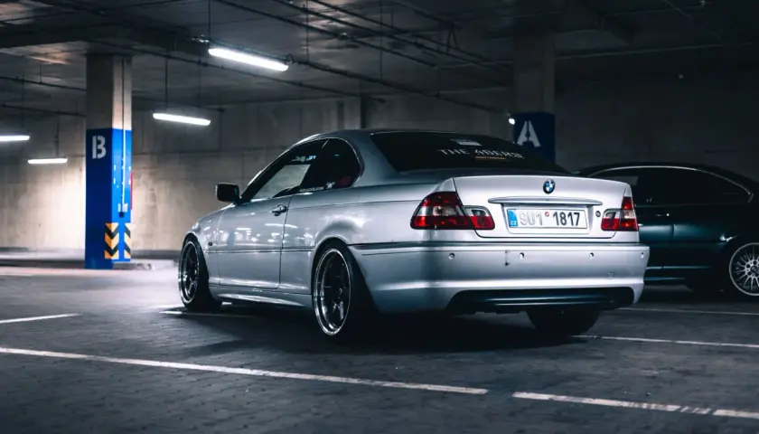 Srebrne BMW serii 3 (m54) z przyciemnianymi szybami i czarnymi felgami stoi na parkingu podziemnym.
