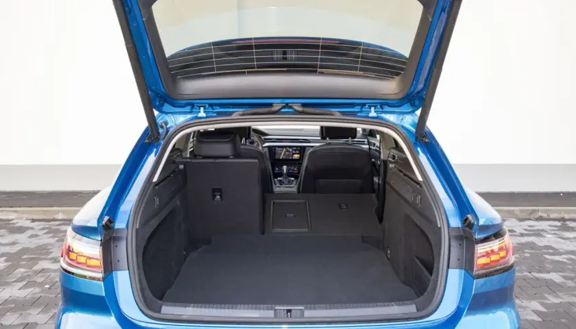 Błękitny Arteon Shooting Brake z otwartym bagażnikiem. Wnętrze jest przestronne, z czarną wykładziną i widocznymi tylnymi siedzeniami.