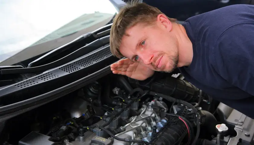 Mechanik nasłuchuje pracy silnika, skupiając się na kolektorze.