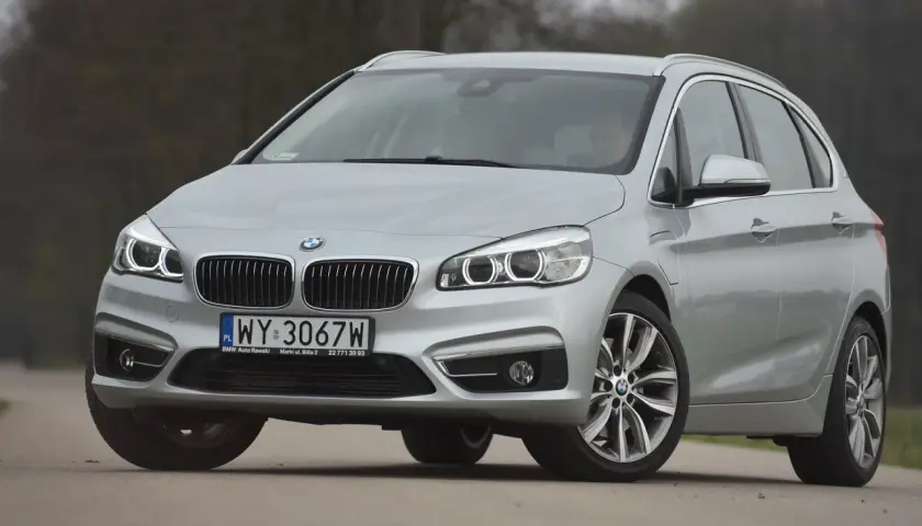 Srebrne bmw 218i na drodze, z przodu widoczna atrapa chłodnicy i reflektory.