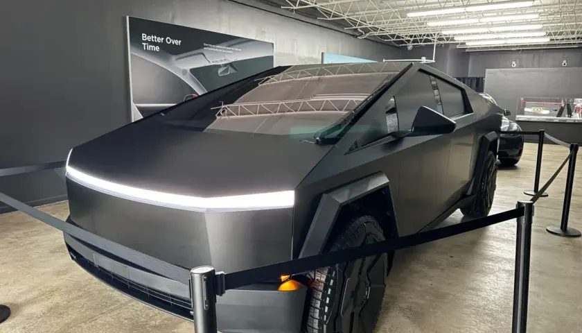 Futurystyczny Cybertruck w matowej czerni, z charakterystycznym pasem LED z przodu, prezentowany na wystawie.
