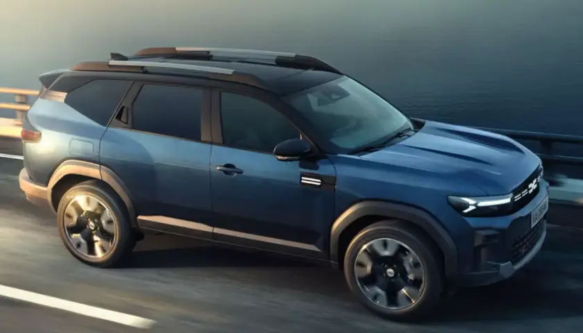 Niebieski Dacia Bigster 2025 na drodze, z nowoczesnym designem i relingami dachowymi.