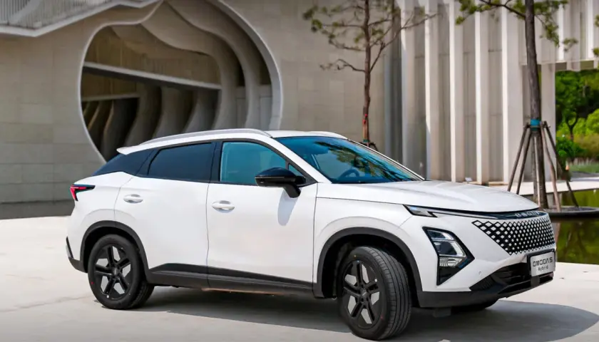 Biały OMODA hybryda zaparkowany przed nowoczesnym budynkiem. Stylowy SUV z charakterystycznym grillem i dynamiczną linią nadwozia.