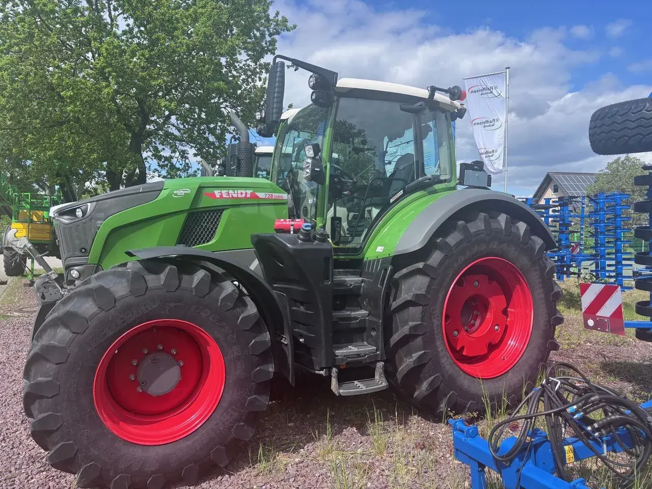 Zielony traktor Fendt 930 Vario z czerwonymi felgami, gotowy do pracy na polu.
