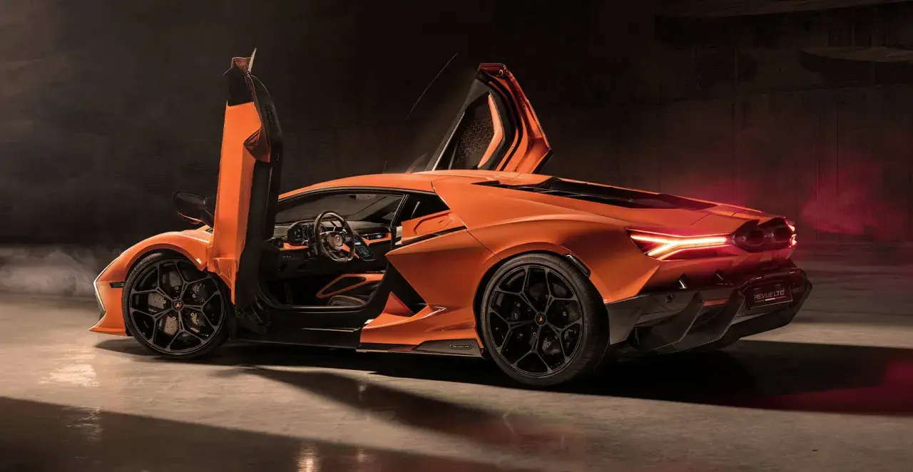 Pomarańczowy Lamborghini Revuelto z otwartymi drzwiami typu nożycowego, z widocznym wnętrzem i sportowymi felgami.