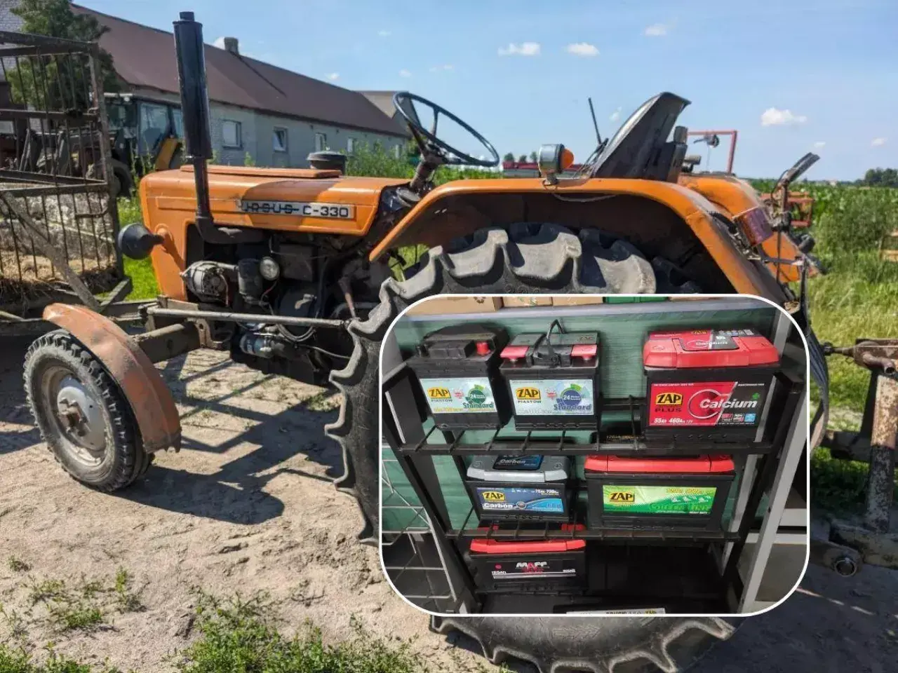 Pomarańczowy Ursus C-330, klasyczny ciągnik rolniczy, stoi na podwórku. W rogu widać półkę z akumulatorami ZAP.