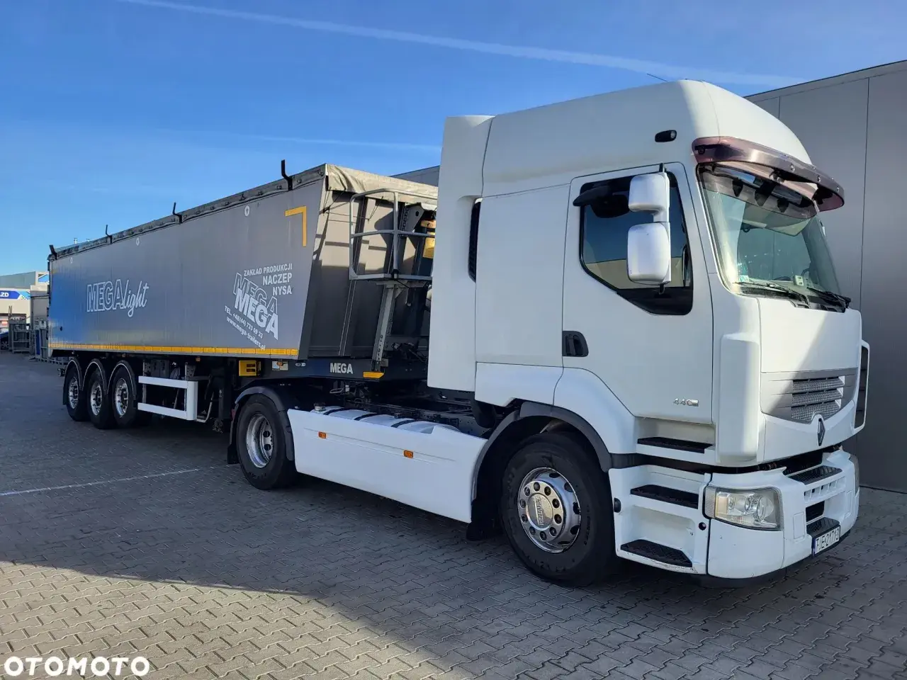 Biała ciężarówka Renault Premium z naczepą MEGA, gotowa do trasy.