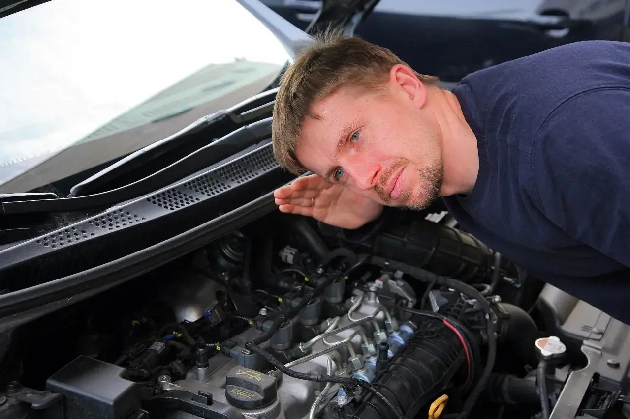 Mechanik nasłuchuje pracy silnika, skupiając się na kolektorze.