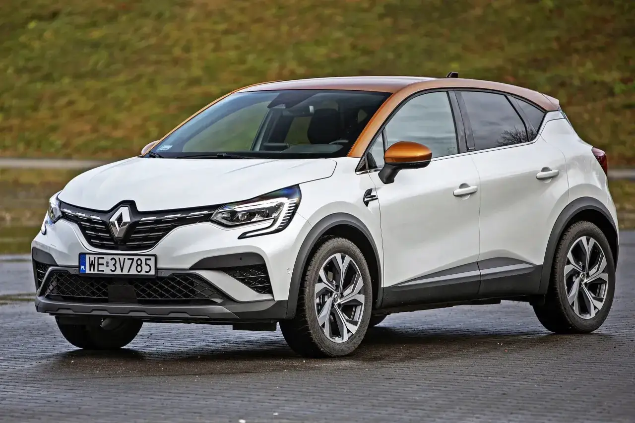Biały Renault Captur z brązowym dachem, jeden z wielu nowoczesnych renault modele, stoi na mokrej nawierzchni.