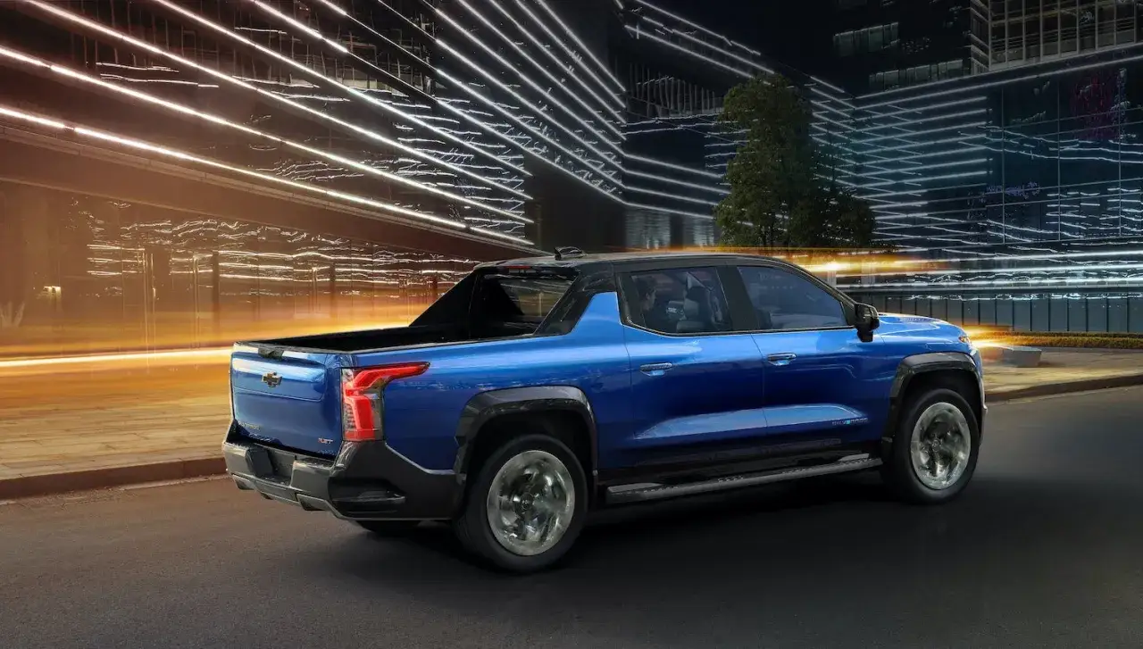 Niebieski Chevrolet Silverado EV, jeden z najnowszych chevrolet modele, jedzie nocą po mieście.