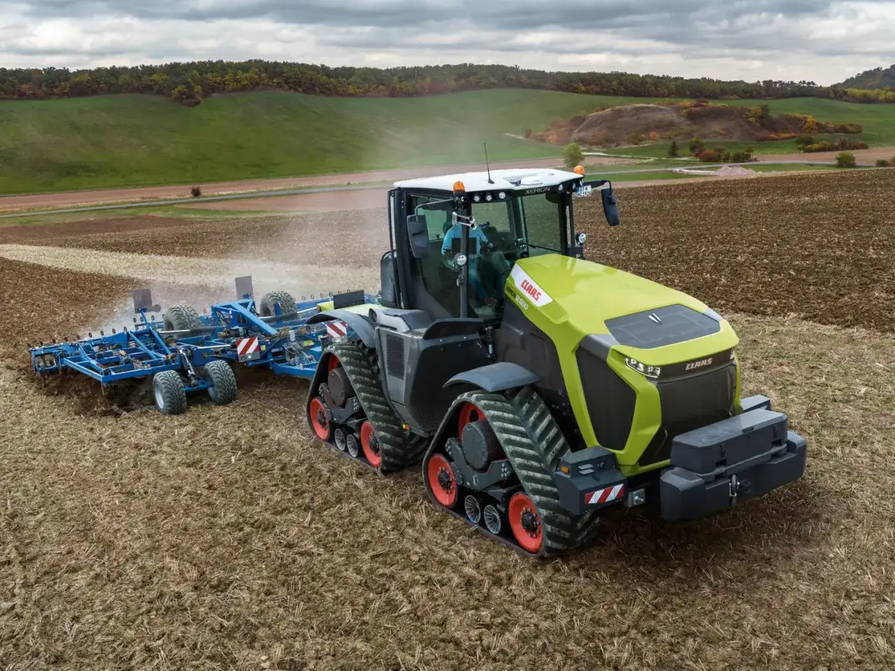 Nowoczesny, gąsienicowy ciągnik CLAAS Xerion 5000 z pługiem obracalnym pracuje na polu, przygotowując ziemię do siewu.