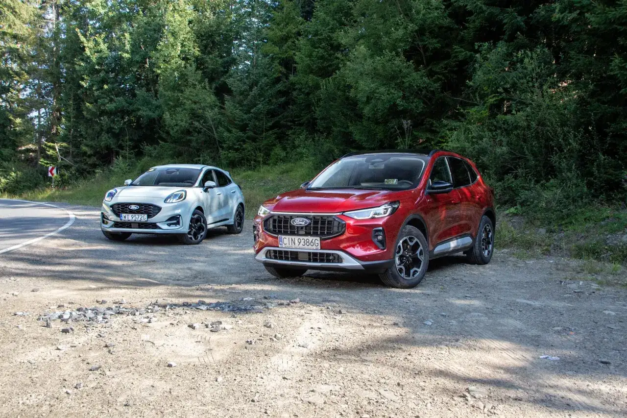 Dwa modele Forda: czerwony SUV i biały crossover, zaparkowane na leśnej drodze.